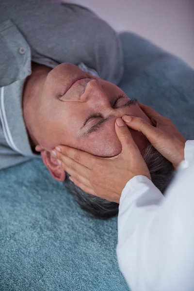 Старший мужчина получает массаж головы от физиотерапевта — стоковое фото
