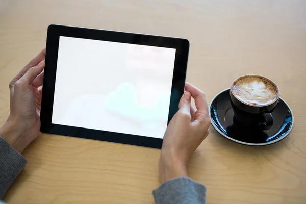 Kobieta za pomocą cyfrowego tabletu filiżankę kawy na stole — Zdjęcie stockowe
