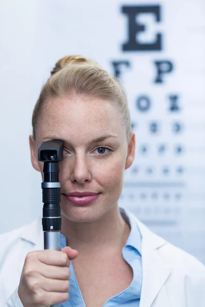 Female optometrist looking through ophthalmoscope — Stock Photo, Image
