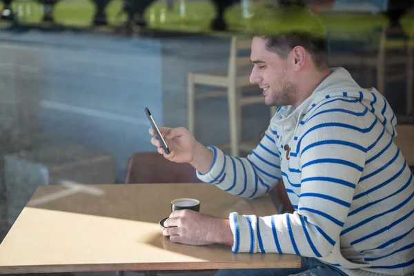 Человек, использующий мобильный телефон в кафе — стоковое фото