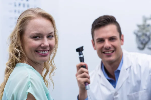 Paciente femenina sonriendo con optometrista de fondo —  Fotos de Stock