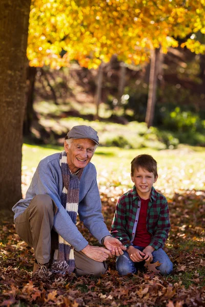 Abuelo y nieto jugando con hojas de otoño — Foto de Stock