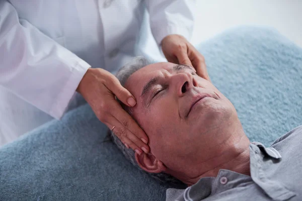 Homem idoso recebendo massagem na cabeça do fisioterapeuta — Fotografia de Stock