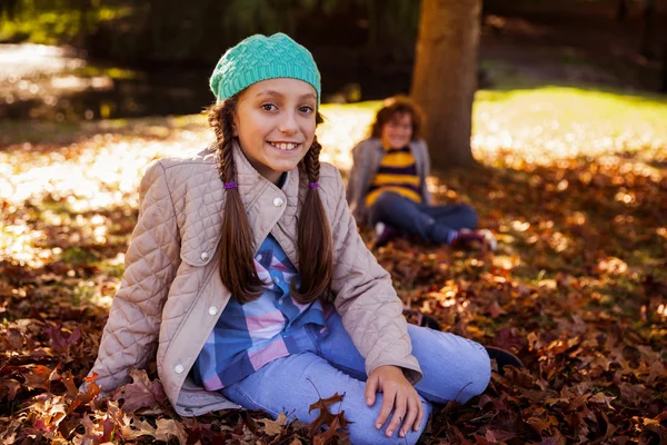 Geschwister sitzen im Herbst im Park — Stockfoto