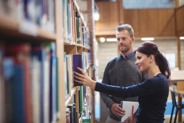 Mature student removing book from shelf Stock Image