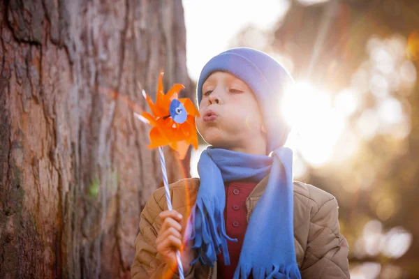 Söt pojke blåser pinwheel — Stockfoto