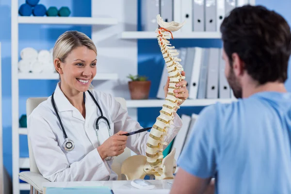 Fisioterapeuta explicando o modelo da coluna vertebral ao paciente — Fotografia de Stock