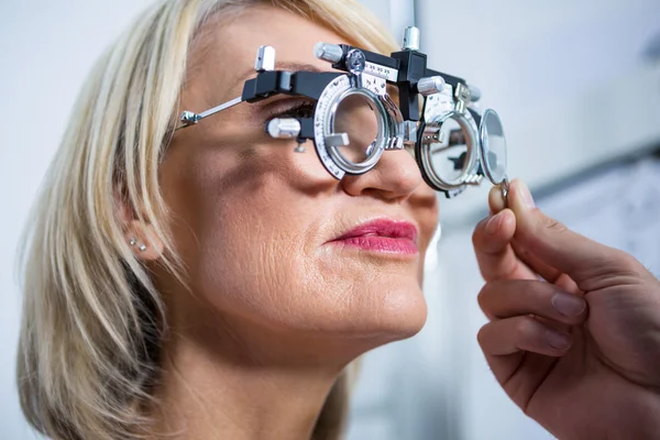 Optometrista examinando paciente femenina con messbrille — Foto de Stock