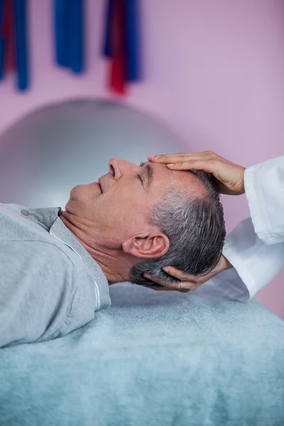 Homme âgé recevant un massage de la tête par un physiothérapeute — Photo