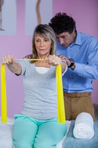 Senior vrouw training met oefening band bijgestaan — Stockfoto