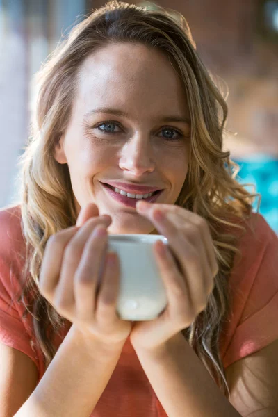 Retrato de una mujer sonriente sosteniendo una taza de café — Foto de Stock
