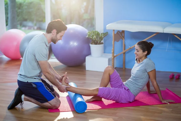 Fisioterapeuta que ayuda a la mujer mientras hace ejercicio — Foto de Stock