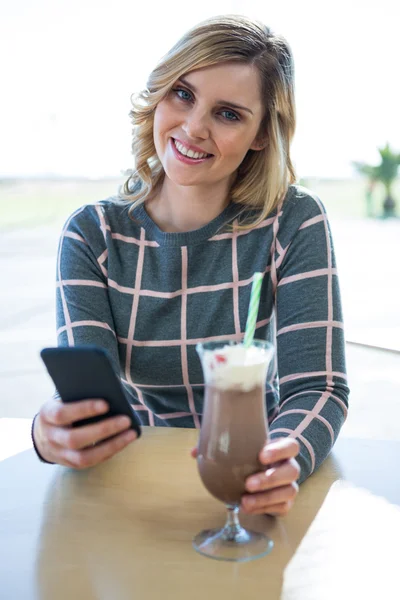 Mulher usando telefone celular enquanto tem milkshake — Fotografia de Stock
