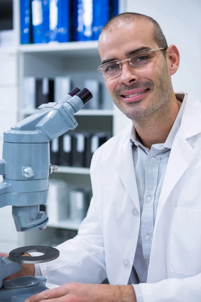 Optometrista maschio sorridente con microscopio — Foto Stock