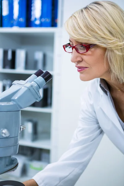 Optométriste féminine regardant à travers le microscope — Photo