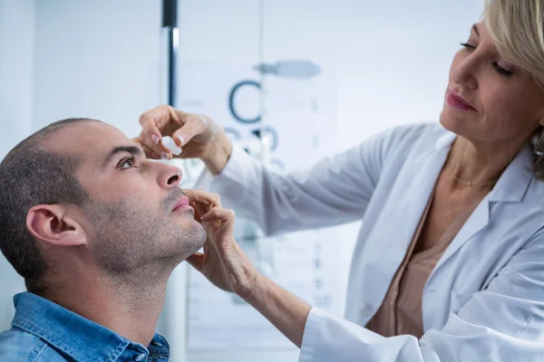 Оптометрист капает пациентам в глаза — стоковое фото