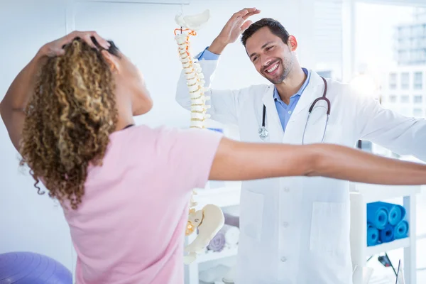 Fisioterapeuta explicando modelo de columna vertebral al paciente — Foto de Stock