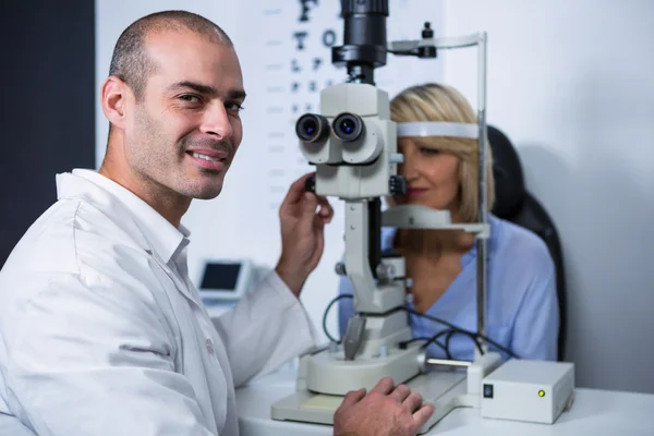Smiling optometrist examining female patient on slit lamp — Stock Photo, Image