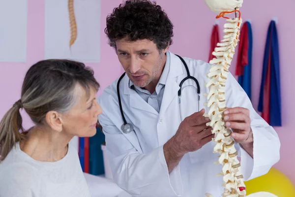 Fisioterapeuta explicando el modelo de columna vertebral al paciente —  Fotos de Stock