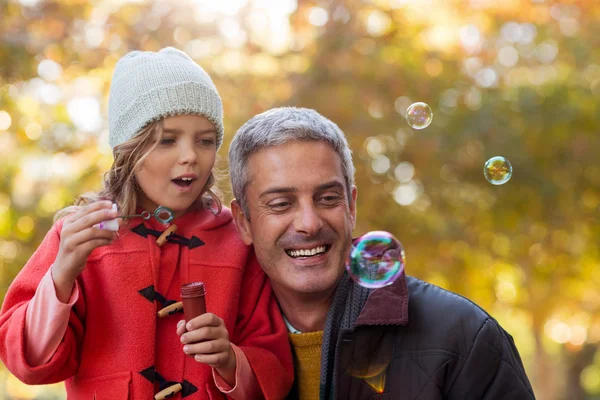 Pai com filha soprando bolhas no parque — Fotografia de Stock
