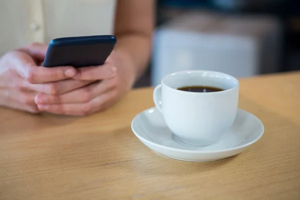 Mujer usando teléfono móvil y una taza de café — Foto de Stock