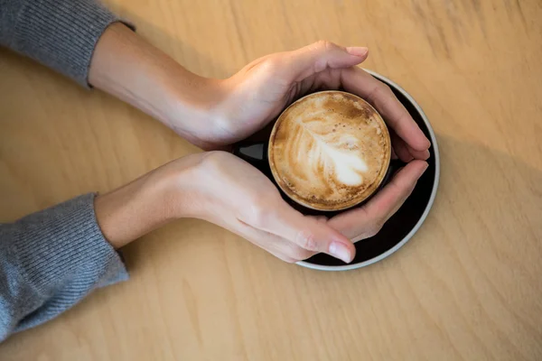 Femme tenant une tasse de café sur la table — Photo