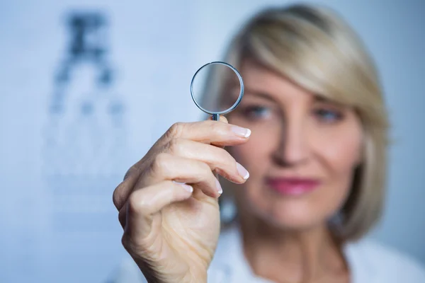 Женщина-оптометрист держит увеличительное стекло — стоковое фото