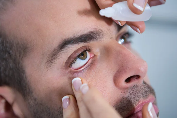 Optometrist putting drops into patients eyes — Stock Photo, Image