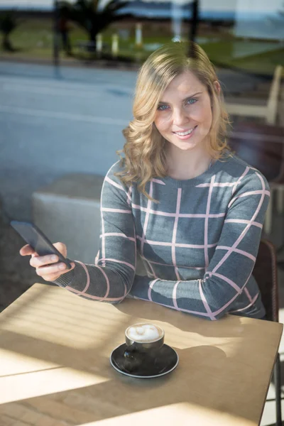 Mujer usando el teléfono móvil mientras toma una taza de café — Foto de Stock