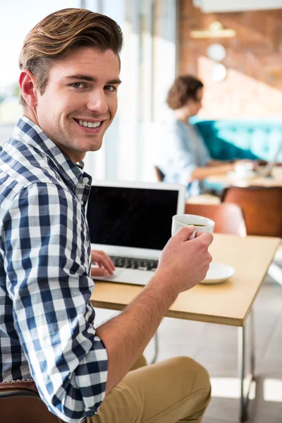 男人微笑着拿着咖啡杯子和使用笔记本电脑的肖像 — 图库照片