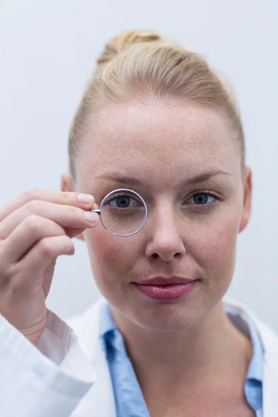 Augenoptikerin blickt durch Lupe — Stockfoto