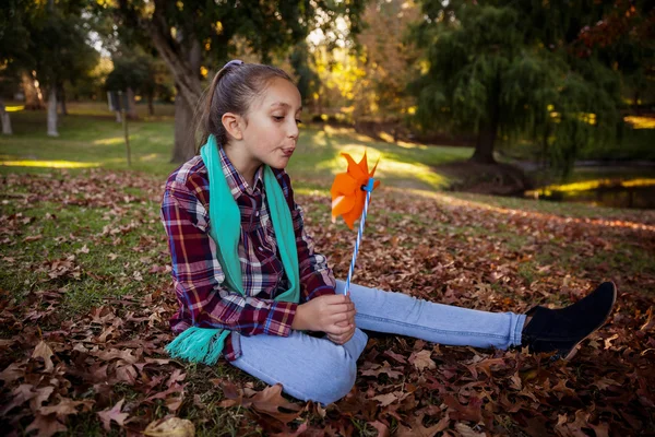 Girl blowing pinwheel in park — Stock Photo, Image