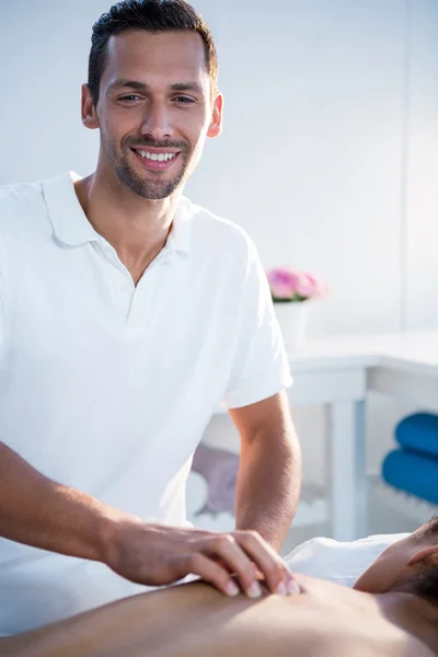 Fisioterapeuta sonriente dando masaje de espalda a una mujer — Foto de Stock