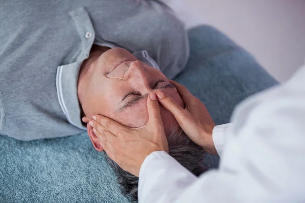 Hombre mayor recibiendo masaje de cabeza de fisioterapeuta — Foto de Stock