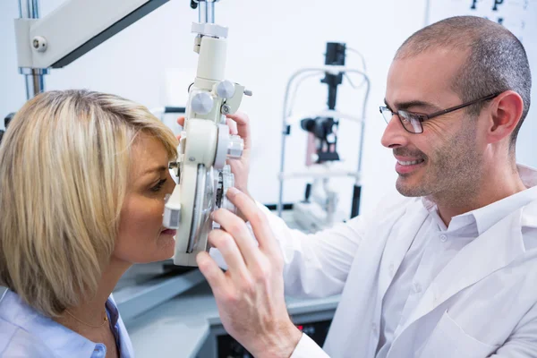 Mosolygó optometrista női beteg a phoropter vizsgálata — Stock Fotó
