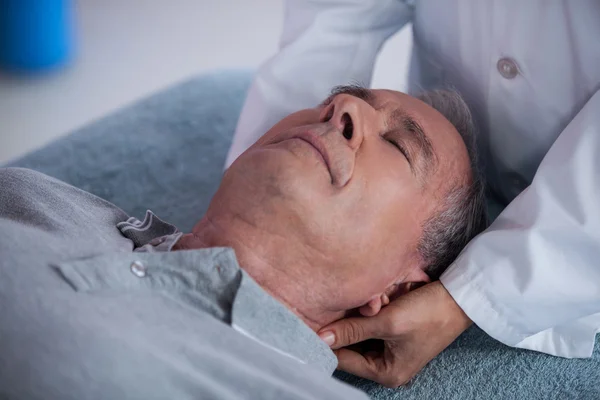 Старший мужчина получает массаж шеи от физиотерапевта — стоковое фото