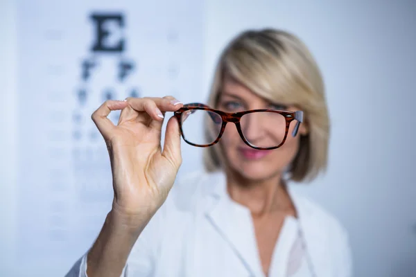 Optometrista femenina sosteniendo gafas —  Fotos de Stock