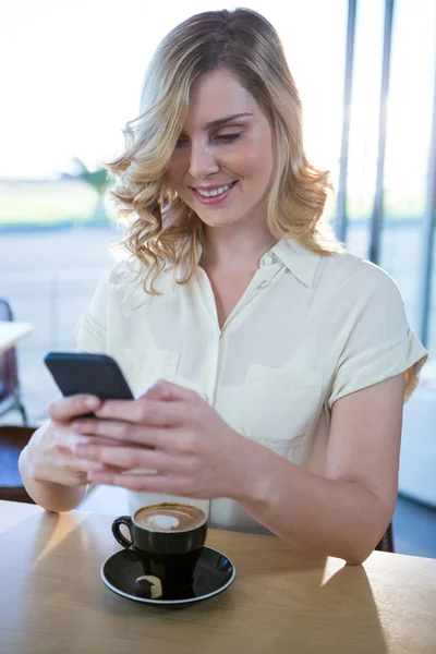 Žena používající mobilní telefon s šálkem kávy v tabulce — Stock fotografie