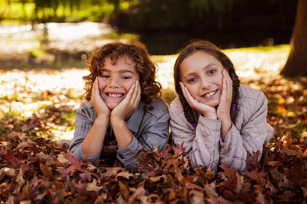 Siblings lying on autumn leaves — Stock Photo, Image