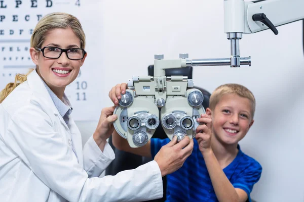 Optik a mladý pacient usmívá pod bude oční test — Stock fotografie