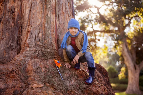 Junge mit Windrad kauert auf Baumstamm — Stockfoto