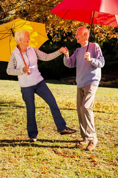 Couple sénior dansant avec des parasols — Photo