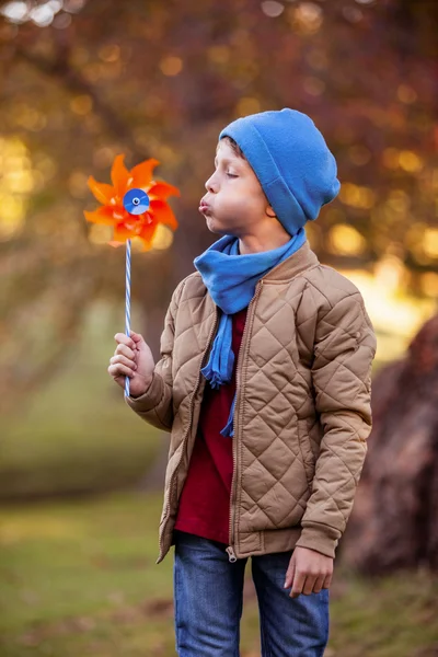 Boy blowing pinwheel at park — Stock Photo, Image