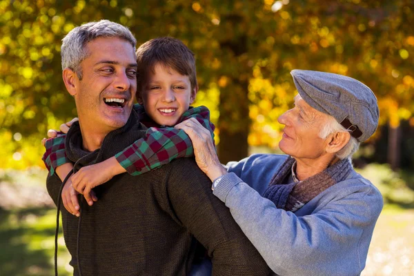 Man piggybacking son while with father — Stock Photo, Image