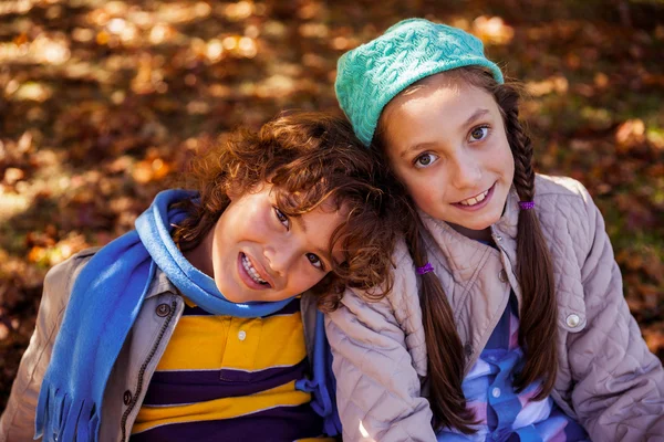 Frères et sœurs souriants assis dans le parc — Photo