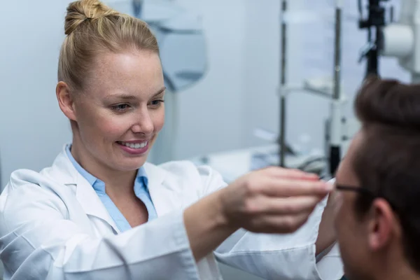 Optometrista feminina que prescreve óculos ao paciente — Fotografia de Stock