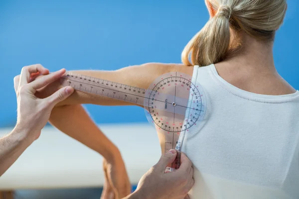 Terapeuta masculino que mide hombro de paciente femenino —  Fotos de Stock