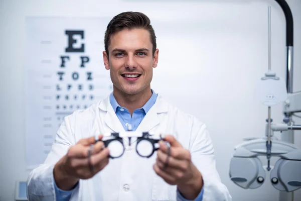 Optometrista sorridente che tiene messbriglia — Foto Stock