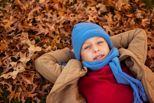 Niño acostado en el parque durante el otoño — Foto de Stock