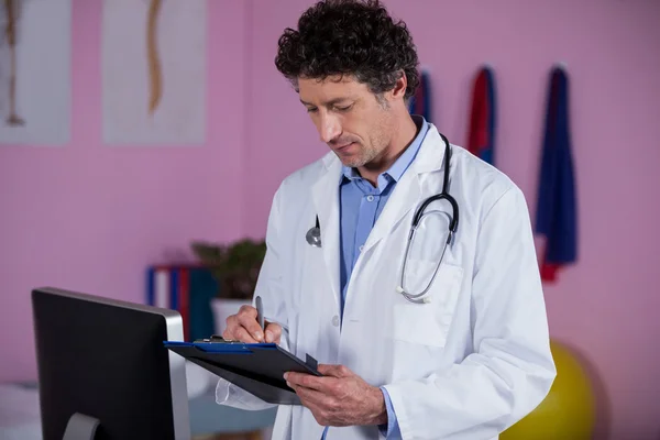 Fisioterapeuta escribiendo en portapapeles — Foto de Stock